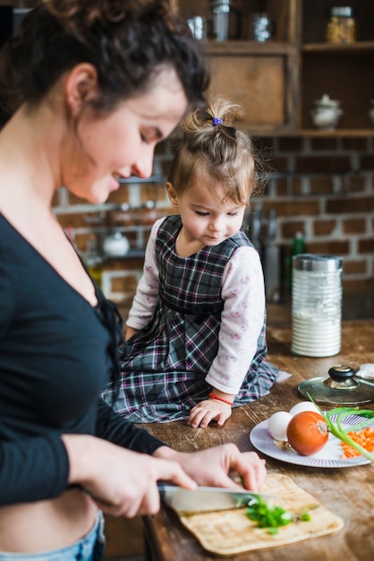 Girl looking at mother cutting onion