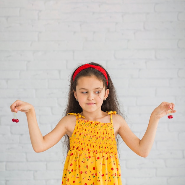 Девочка смотрит на красные вишни, держа в руках