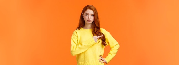 Free photo girl looking upset and unsatisfied sad sulky redhead woman pointing left with envy or jealousy cant