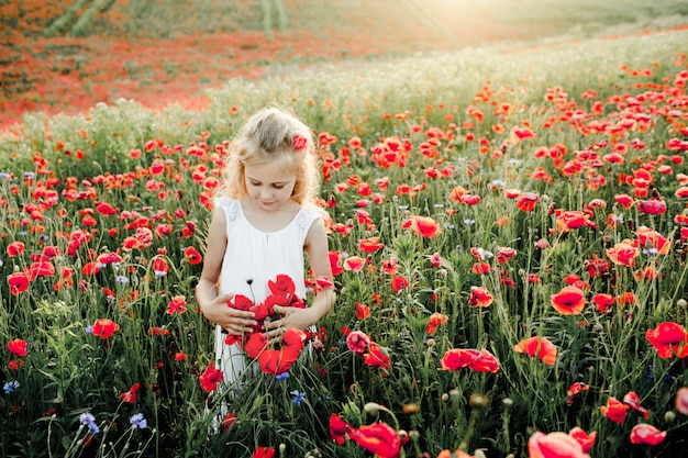 Girl looks at poppy flowers