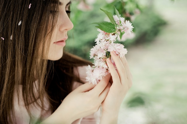 Foto gratuita la ragazza esamina il ramo di sakura nel parco