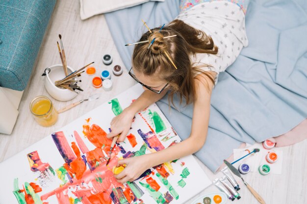 Girl lying on floor and painting with gouache 