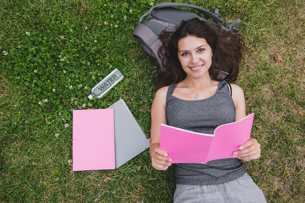 Free photo girl lying on grass holding notebook