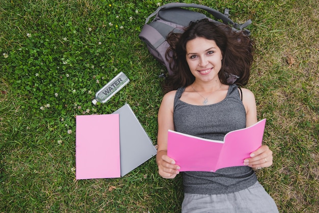 Girl lying on grass holding notebook