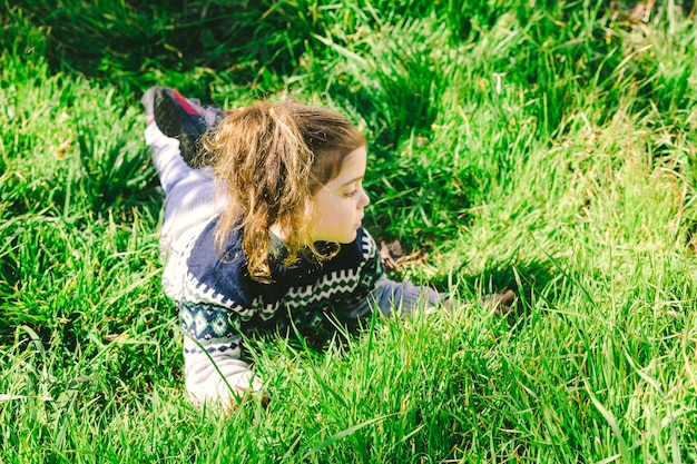 Foto gratuita ragazza sdraiata sull'erba e guardando lontano