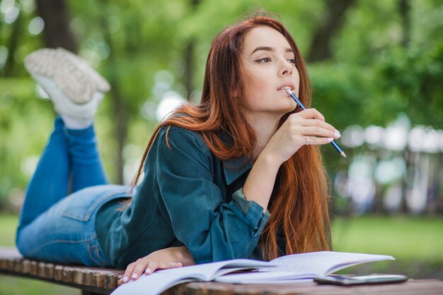 Girl lying on table biting pencil