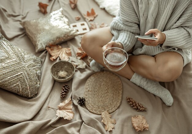 Девушка делает фото чашки чая среди осенних листьев, осенней композиции.