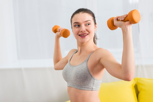 Girl making exercise with dumbbell in her house