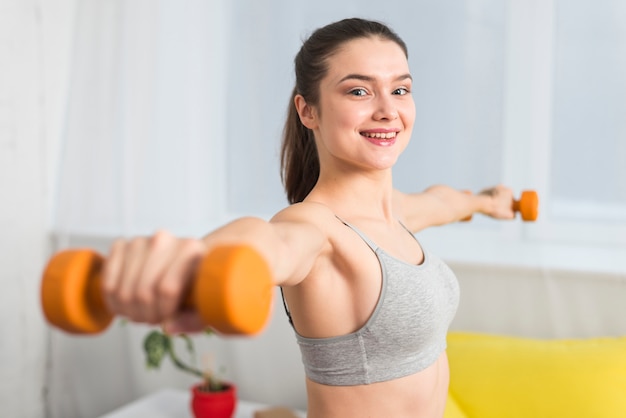 Girl making exercise with dumbbells in her house