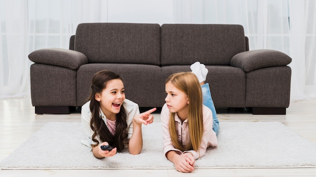 Foto gratuita ragazza facendo furberia della sua amica sdraiata sul tappeto a casa