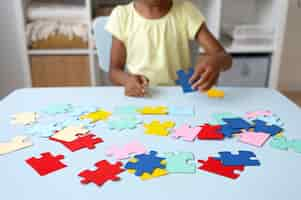 Free photo girl making puzzle at table front view