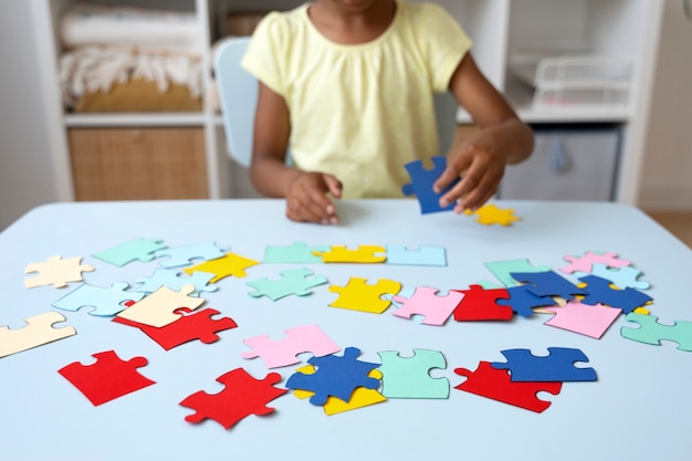 Girl making puzzle at table front view