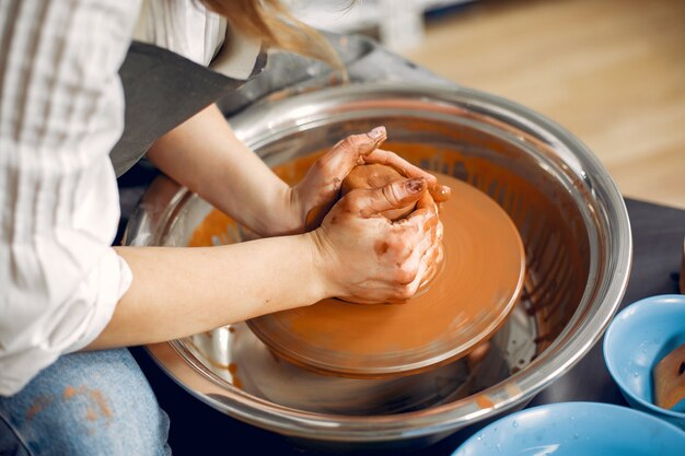 陶器の機械で粘土から迷路を作る女の子