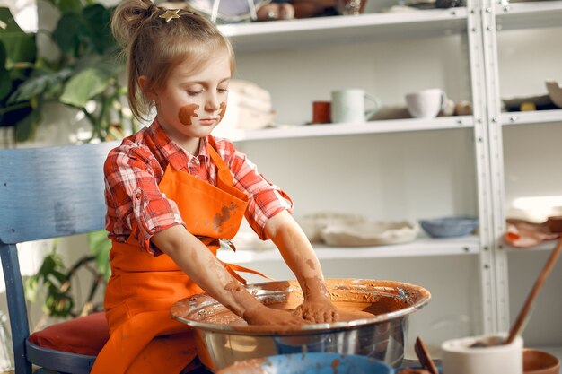 Girl making a vaze from a clay on a pottery's machine