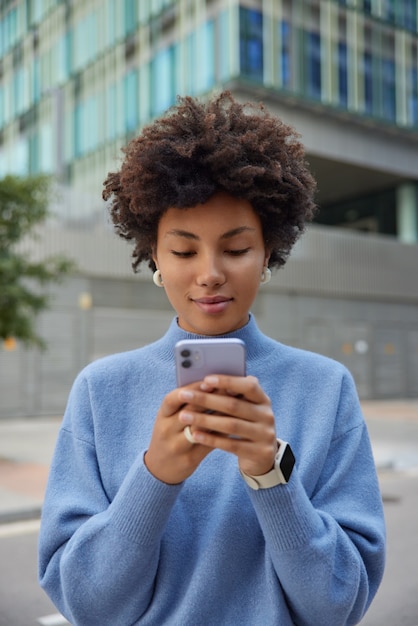モバイルアプリケーションを介した女の子のメッセージは、レジャーでスマートフォン接続を使用して、街でソーシャルメディアのネットワーキングを楽しんでいます。