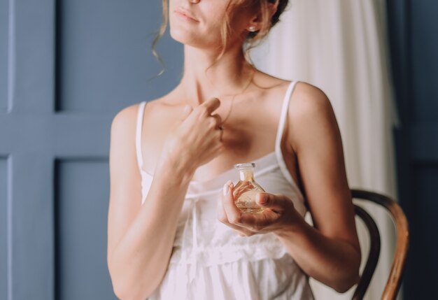 girl in the morning uses a perfume around her neck