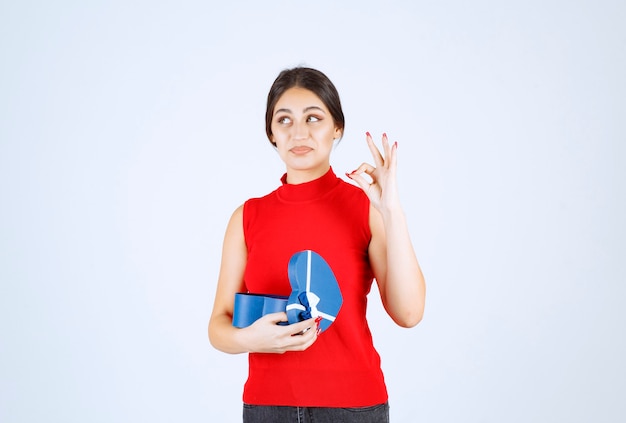 Girl opening a blue gift box and enjoying the present.