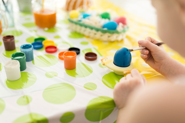 Girl painting Easter egg with blue