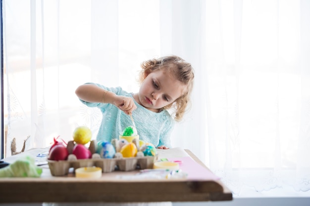 Girl painting eggs with brush