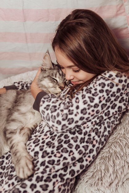 Girl in pajamas hugging her fluffy cat