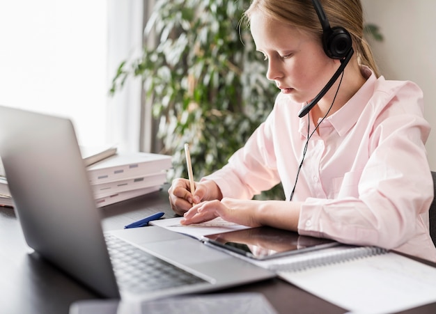 Girl participating at an online class while writing