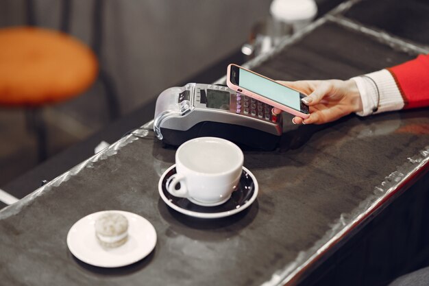 Girl paying for her latte with a smartphone by contactless PAY PASS technology