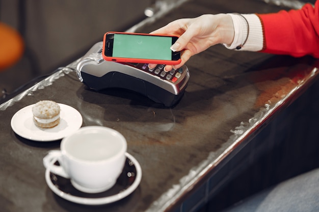 Girl paying for her latte with a smartphone by contactless PAY PASS technology