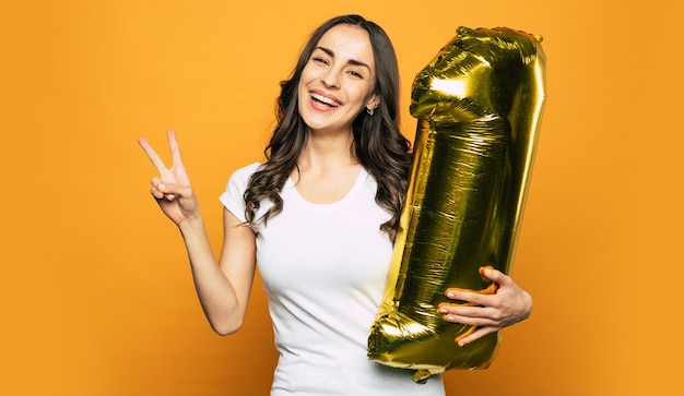 A girl on the photo is celebrating her personal achievement with gold balloon in a shape of number one