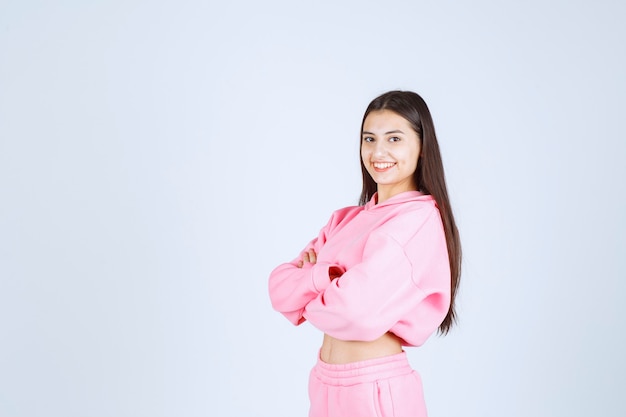 Girl in pink pajamas crossing arms and smiling. 