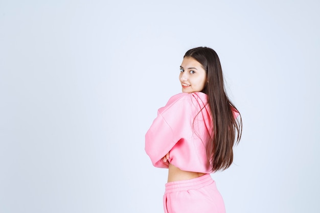 Girl in pink pajamas crossing arms and smiling. 