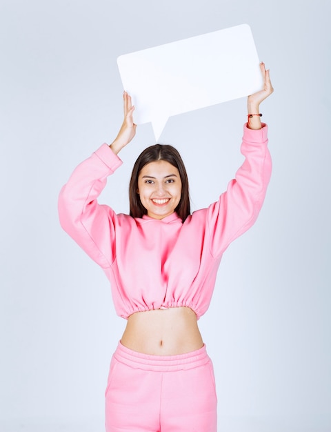 Girl in pink pajamas holding a blank rectangular ideaboard over her head and thinking. 