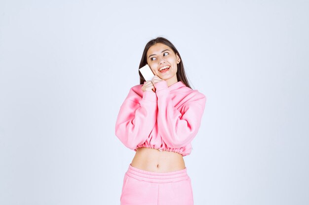 Girl in pink pajamas holding a business card and introducing herself to her business partners. 