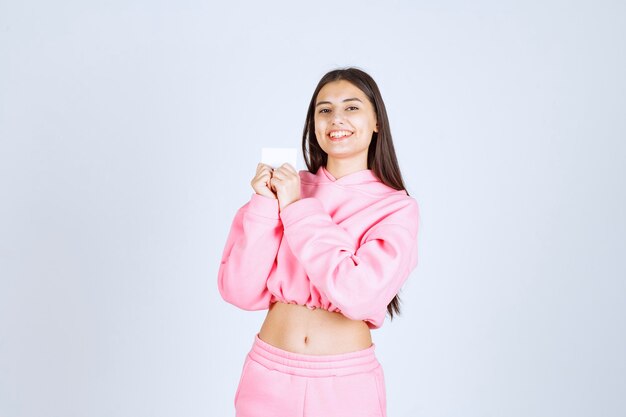 Girl in pink pajamas holding a business card and introducing herself to her business partners. 