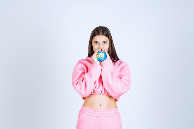 Ragazza in pigiama rosa che tiene un mini globo tra le mani.