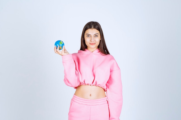 Girl in pink pajamas holding a mini globe in her hand. 