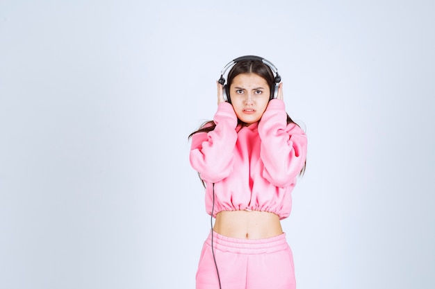 ヘッドフォンを聞いているピンクのパジャマを着た女の子で、音楽が好きではありません。