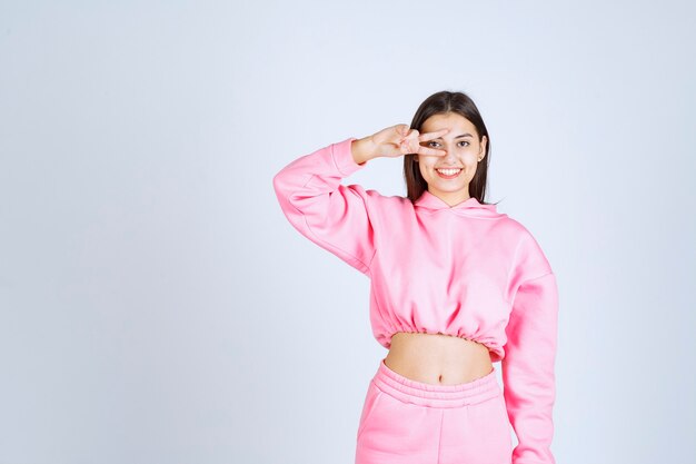 Girl in pink pajamas looking through her fingers