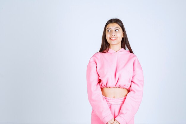Girl in pink pajamas looks confused and doubtful