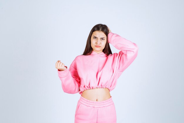 Girl in pink pajamas looks confused and thoughtful