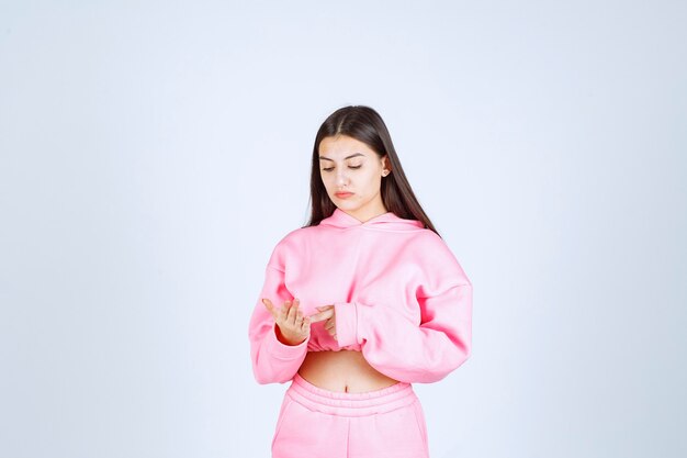 Girl in pink pajamas looks confused and thoughtful