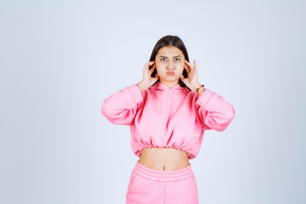 Girl in pink pajamas looks confused and thoughtful