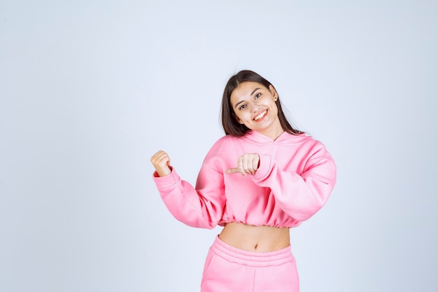 Girl in pink pajamas looks sportive and shows her fists