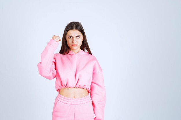 Girl in pink pajamas looks sportive and shows her fists