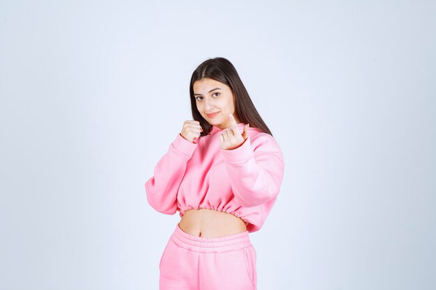 Girl in pink pajamas looks sportive and shows her fists