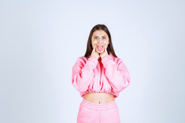Девушка в розовой пижаме, указывая на ее рот
