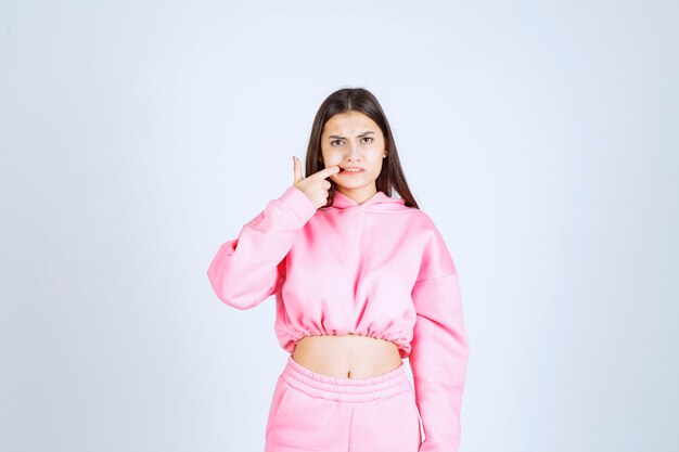 Girl in pink pajamas pointing at her mouth