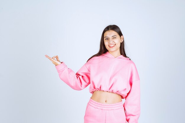 Girl in pink pajamas pointing at something on the left