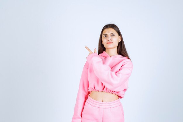 Girl in pink pajamas pointing at something on the left