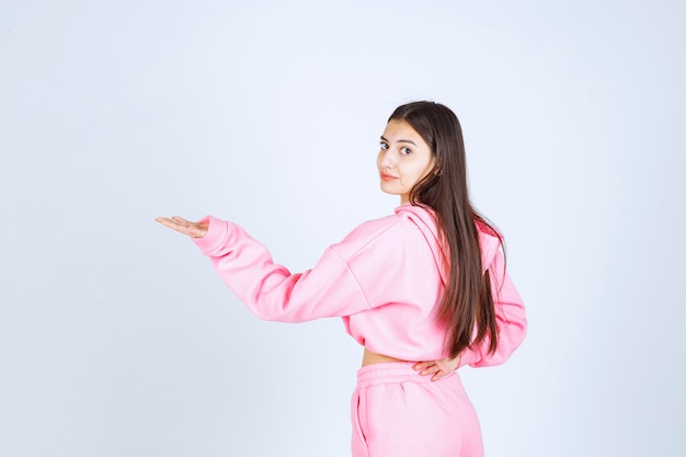 Girl in pink pajamas pointing at something on the left