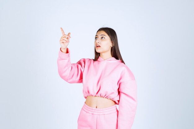 Girl in pink pajamas pointing at something on the left